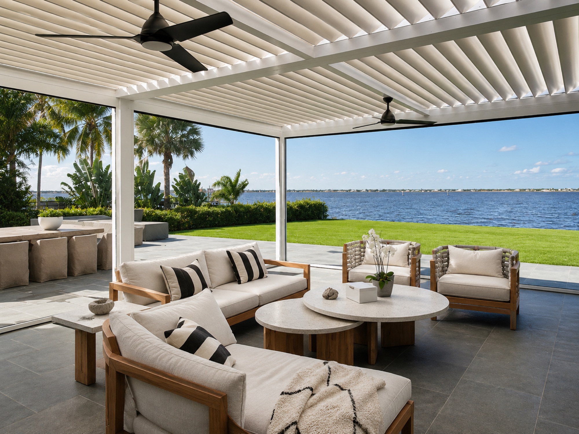 Waterfront covered outdoor living lounge under a louvered pergola with bay views, southwest Florida
